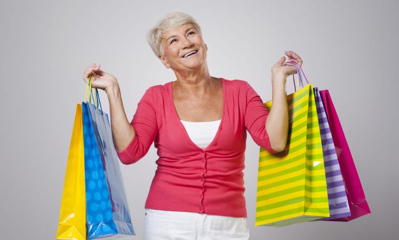 #PraCegoVer: Imagem de uma senhora segurando sacolas de compras.