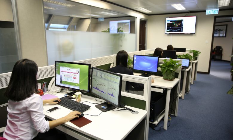 #PraCegoVer: Imagem de um escritório com três mesas em fileira e pessoas trabalhando.