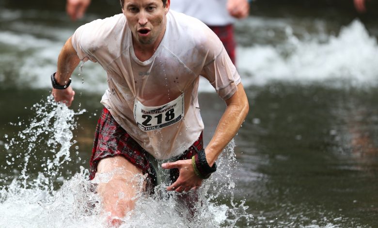 #PraCegoVer: Homem correndo em uma corrida de obstáculos em um rio.