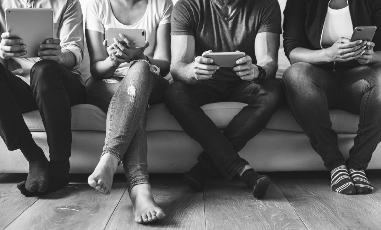 #PraCegoVer: Imagem de um grupo de pessoas utilizando celulares.