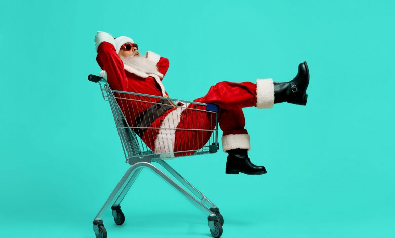 #PraCegoVer: Imagem de um Papai Noel dentro de um carrinho de supermercado.